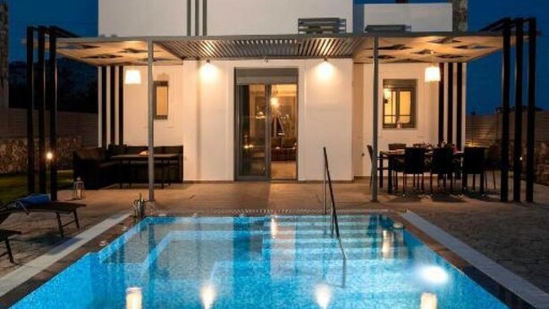Une maison moderne dotée d’une piscine, d’un espace salon extérieur et d’un patio couvert.