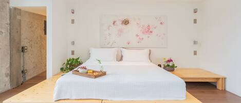 A spacious bedroom with a large bed, wooden bench, and a wall-mounted light fixture.