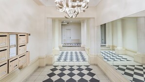 A hallway with a checkered floor, a mirrored wall, and a modern chandelier. - Merveil - Luxury Suite - Louvre - Ours I (Paris)
