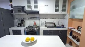 A kitchen with white cabinets, a stove, a sink, and a white countertop.