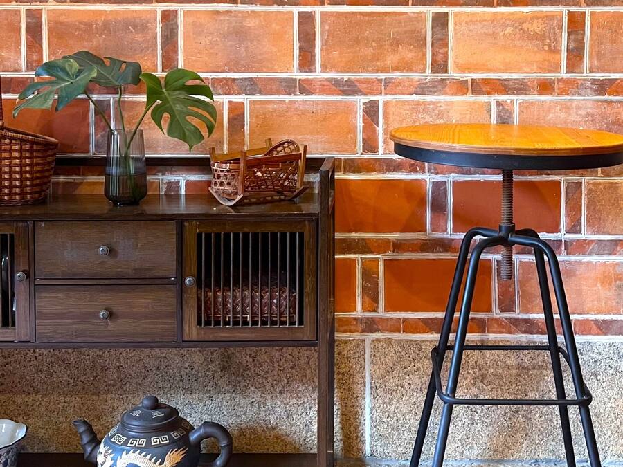 A wooden cabinet with drawers, a wicker basket, a green vase, and a potted plant.
