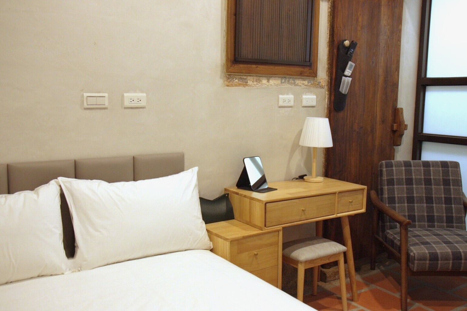 Een hotelkamer met een bed, een bureau met lamp, een stoel en een klein tafeltje.