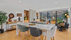 Een moderne woonkamer met een eethoek, grote ramen en uitzicht op bergen.