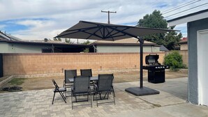 An outdoor patio with a brick floor, a table with chairs, a barbecue grill, and a large umbrella. - 3-bedroom farm stay just 13 minutes from Santa Anita Park (Azusa)