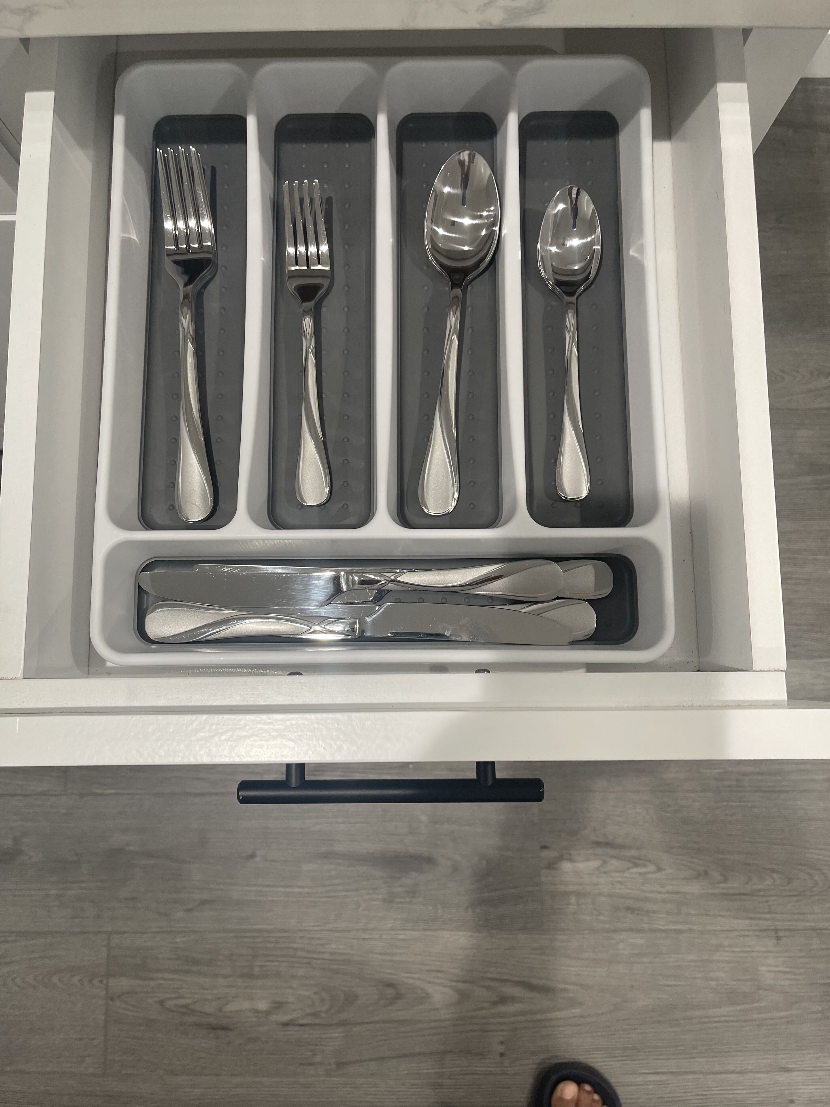 A drawer containing neatly arranged cutlery including forks, spoons, and knives.