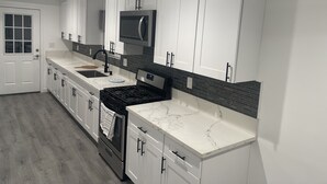 A modern kitchen with white cabinetry, a stainless steel range, a microwave, and a tiled backsplash. - 3-bedroom farm stay just 13 minutes from Santa Anita Park (Azusa)
