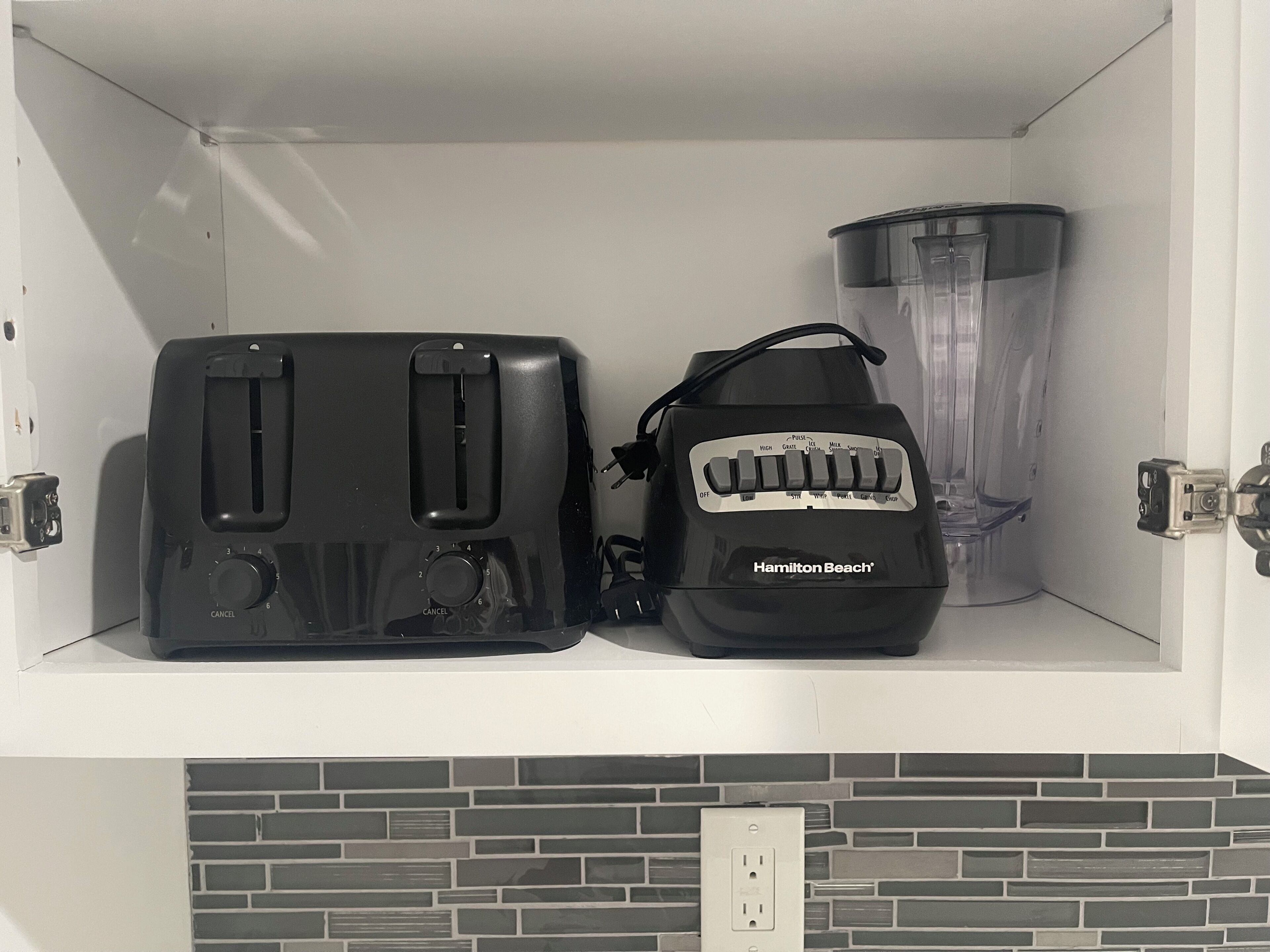 Cozinha com torradeira, liquidificador e painel de fundo em padrão de tijolos.