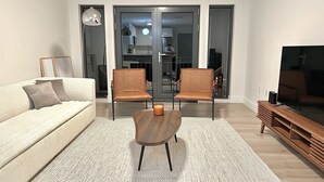 A modern living room with a sofa, two chairs, a coffee table, and a TV. - Luxury 2 Bedroom Apartment in Heart of Quincy (Quincy)