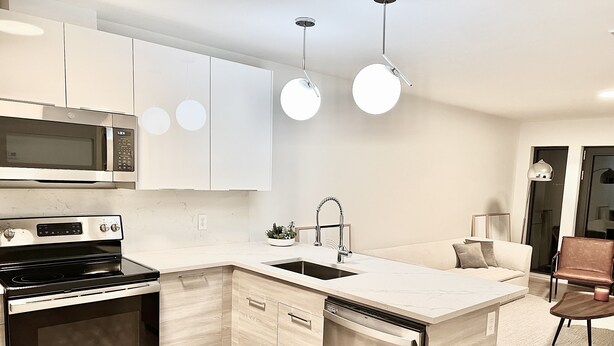 A modern kitchen with a built-in microwave, stove, and dishwasher, a sink, and pendant lighting. - Luxury 2 Bedroom Apartment in Heart of Quincy (Quincy)
