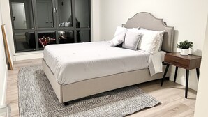 A bedroom with a bed, a nightstand, a mirror, and a wardrobe. - Luxury 2 Bedroom Apartment in Heart of Quincy (Quincy)