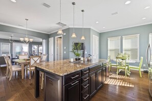 A spacious kitchen with granite countertops, dark cabinetry, and pendant lighting.