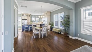 A spacious kitchen with a central island, white cabinetry, and a dining area with chairs. - Sunset Inlet Luxury Oasis | Ocean Views | Private Beach Access | Boat Slip | Beverly Beach | Dogs Ok (Flagler Beach)