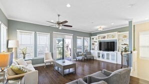 A spacious living room with a ceiling fan, a TV, and a fireplace. - Sunset Inlet Luxury Oasis | Ocean Views | Private Beach Access | Boat Slip | Beverly Beach | Dogs Ok (Flagler Beach)