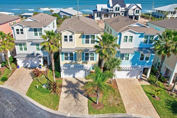 A coastal residential area with houses featuring a uniform architectural style, including gabled roofs and a central garage.