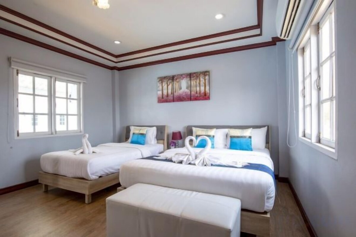 A hotel room with two beds, a large window, and a painting on the wall.