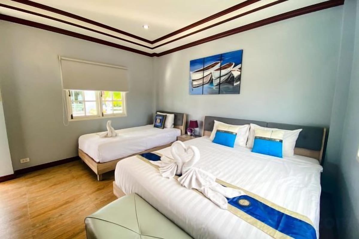 A hotel room with two beds, a window, and a painting on the wall.