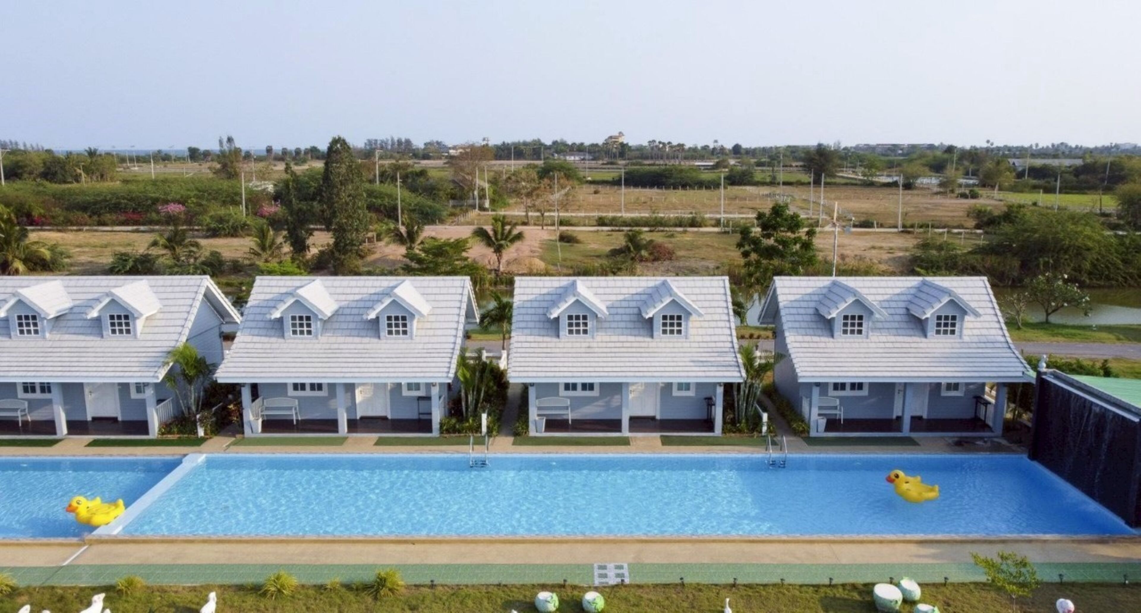 Una hilera de casas blancas con piscina al frente.
