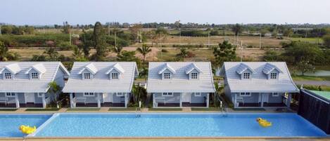 Una hilera de casas blancas con piscina al frente.