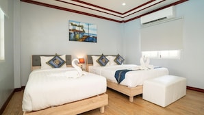 Une chambre d’hôtel avec deux lits, un tableau au mur, un appareil de climatisation et une fenêtre avec des stores.