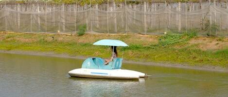 A boat with a person holding an umbrella on a calm river.