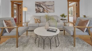 A living room with a grey sofa, two armchairs, a round coffee table, and a marble artwork on the wall. - Canyonview Craftsman Near All Things San Diego! (San Diego)