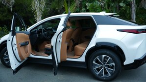 Ein weißer SUV mit beiger Innenausstattung, offene Türen und ein sichtbarer Fahrersitz.