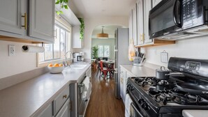 Une cuisine moderne équipée d’une cuisinière à gaz, d’un four à micro-ondes et d’appareils électroménagers en acier inoxydable.