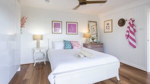 A bedroom with a white bed, a ceiling fan, and a wooden floor. - Bimbajong Studio - Pet Friendly- Oceanstays (Yamba)