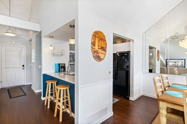 A modern kitchen with a built-in island, bar stools, and a large mirror.