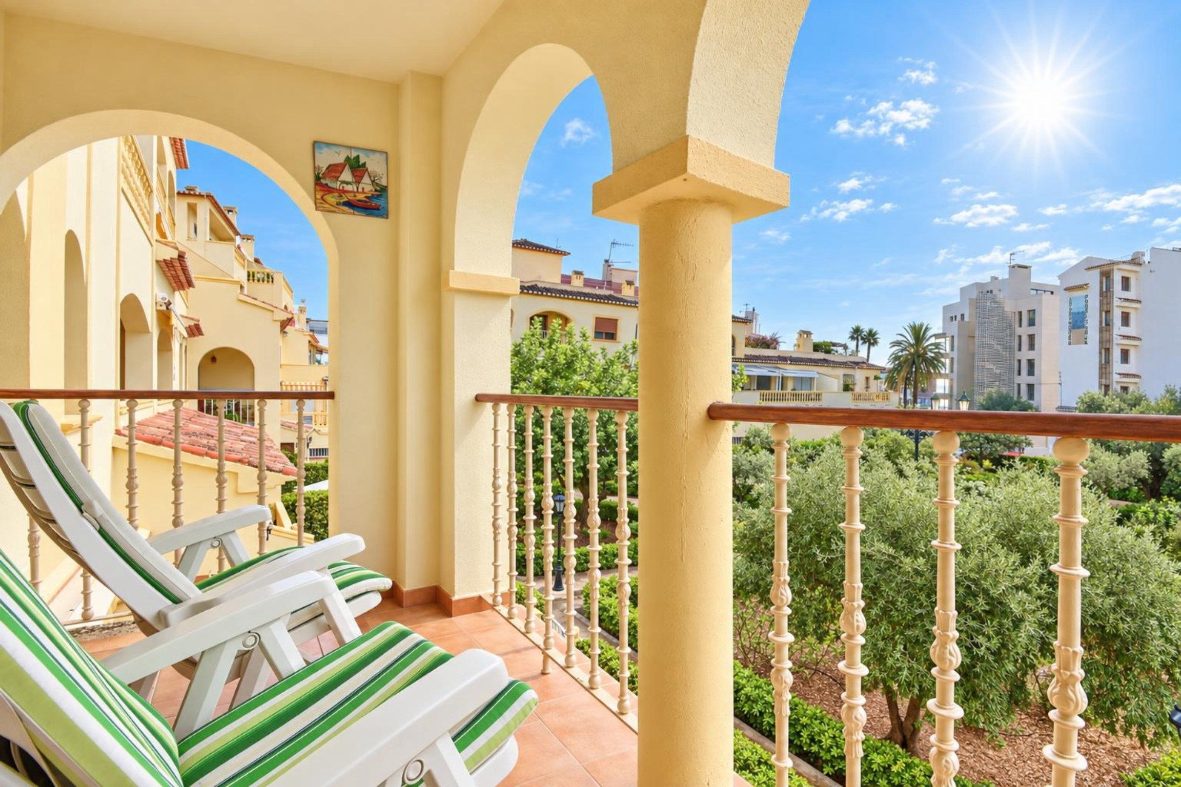 A balcony with a view of buildings and greenery.