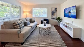 Un salon moderne avec un canapé, une table basse, un téléviseur et des œuvres d’art.