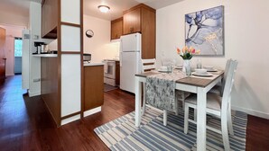 Une cuisine moderne avec des meubles en bois, un réfrigérateur blanc et un coin repas avec une table mise pour deux personnes.
