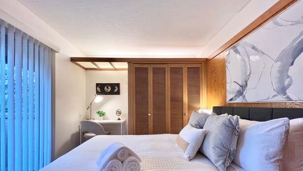 Une chambre d’hôtel avec un grand lit, un bureau, une chaise, une armoire et un tableau au mur.
