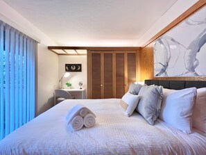 Habitación de hotel con una cama grande, un escritorio, una silla, un armario y un cuadro en la pared.
