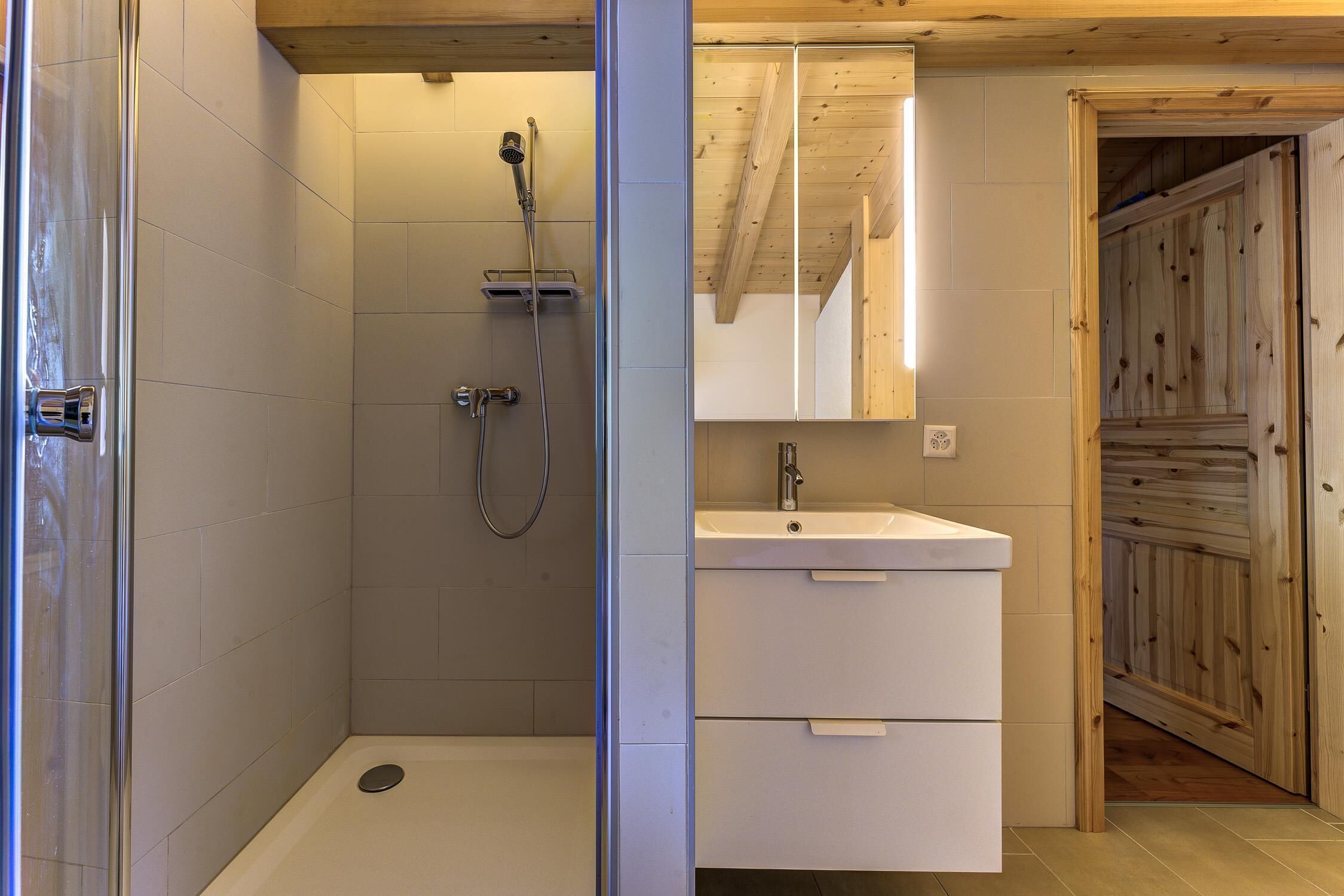 Un bagno moderno dotato di doccia, lavabo e specchio.