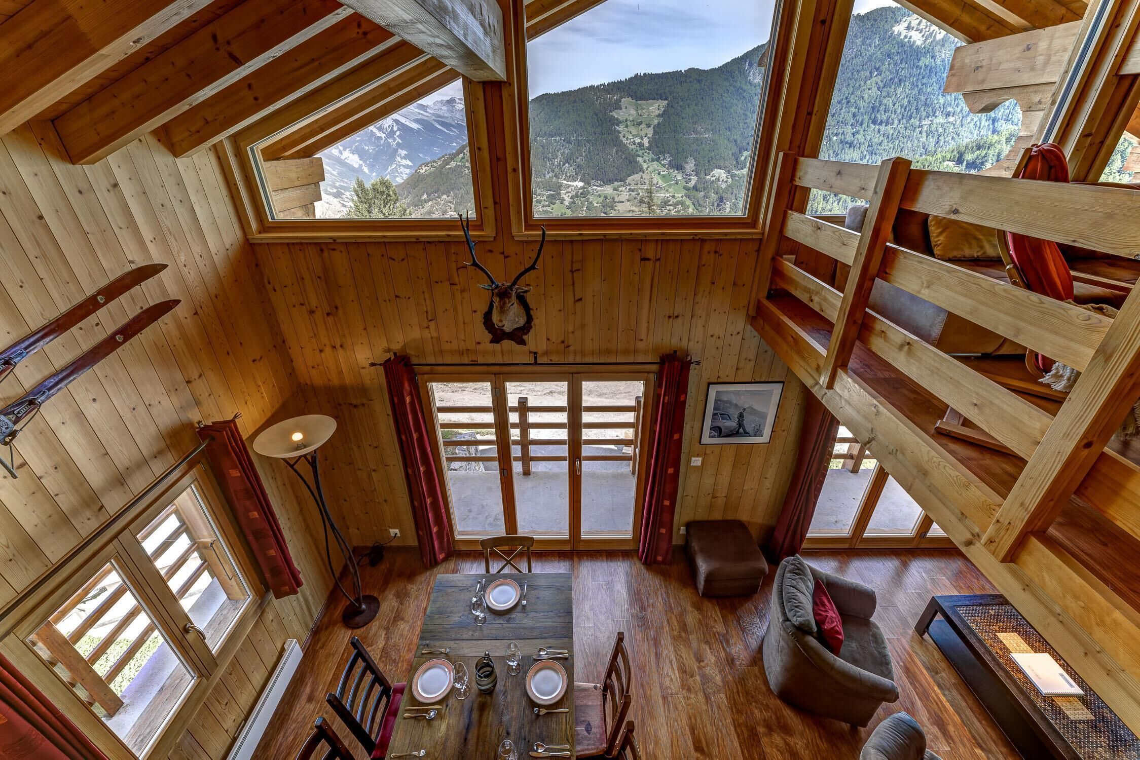 Eine Holzhütte mit Essbereich, Schlafzimmer im Obergeschoss und Blick auf eine Berglandschaft.
