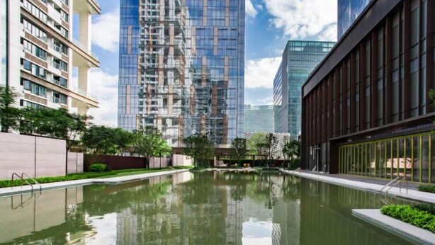 A modern building complex with a central reflective water feature, surrounded by high-rise buildings and greenery. - fuan hotel (Shenzhen)