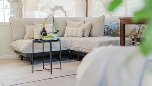A modern living room with a sofa, a small table with a bottle and grapes, and a lamp. - Vacation home Serena by Interhome (Rio Marina)