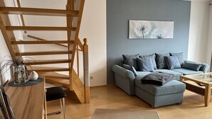 A modern living room with a wooden staircase, a grey sofa, and a coffee table. - Müller (App. 11 ) by Interhome (Zinnowitz)