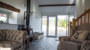 A cozy living room with a fireplace, a sofa, and a chair with a patterned design. - The Hidden Place (Penrith)