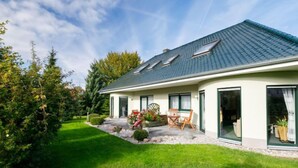 A modern house with a sloped roof, a patio with outdoor furniture, and a well-maintained garden. - Schneider by Interhome (Zinnowitz)