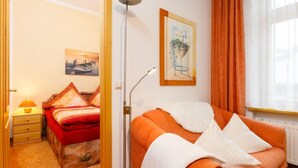 Een kamer met een bed, een bank, een vloerlamp en een raam met gordijnen.