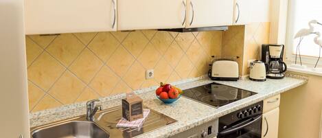 A kitchen with a Bosch dishwasher, a toaster, a coffee maker, and a bowl of fruit on the counter.