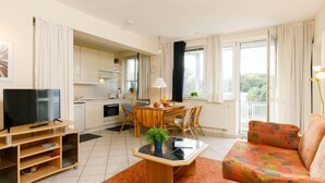 A modern living room with a TV, a dining area, and a kitchen. - Zur Düne II by Interhome (Zinnowitz)
