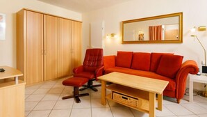 A room with a wooden wardrobe, a red leather chair, a wooden coffee table, and a red sofa. - Zur Düne I by Interhome (Zinnowitz)