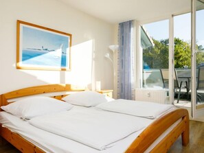 A bedroom with a wooden bed, a view of the outdoors through a sliding glass door, and a framed picture on the wall.