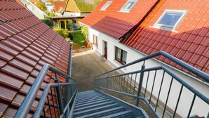 Ett bostadsområde med röda tegeltak, en trappa som leder upp till en vit byggnad och en klar himmel.