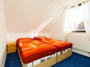 Een slaapkamer met een bed, nachtkastje en een raam met gordijnen.