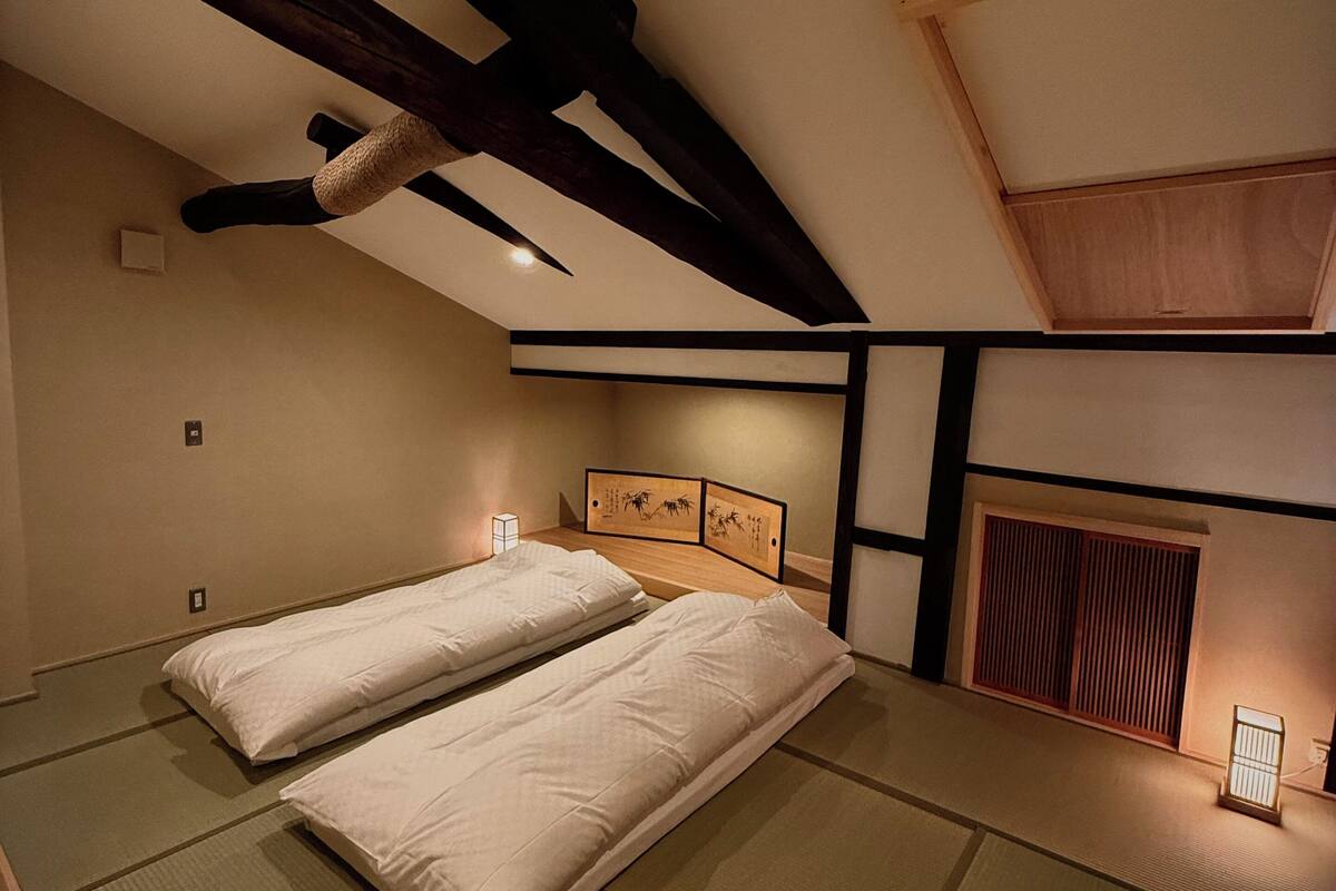 Een traditionele Japanse kamer met tatami vloerbedekking, twee enkele bedden, een plafondventilator en een shoji schuifwand.