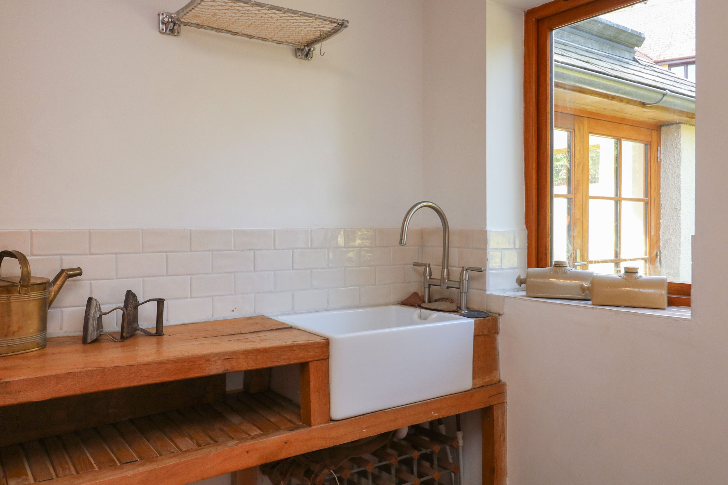 A kitchen with a wooden countertop, white sink, and a window with a view of the outside.
